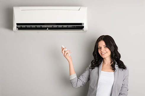 Lady pointing remote at air conditioner
